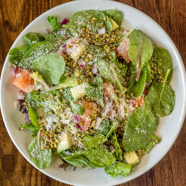 Overhead view of a vibrant Indian salad with greens, sprouts, grapefruit, and shredded coconut.