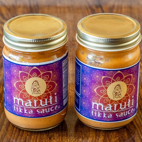 Two jars of Maruti Tikka Sauce with purple and gold labels on a wooden surface.
