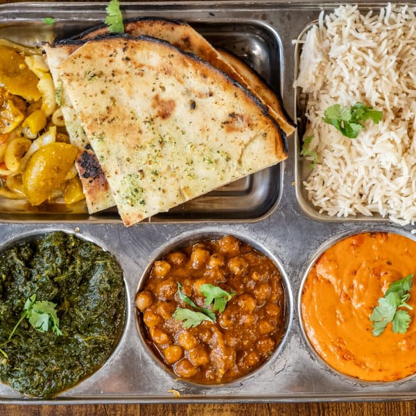 A Maruti Indian Restaurant thali with naan, rice, saag, chana masala, and butter chicken.
